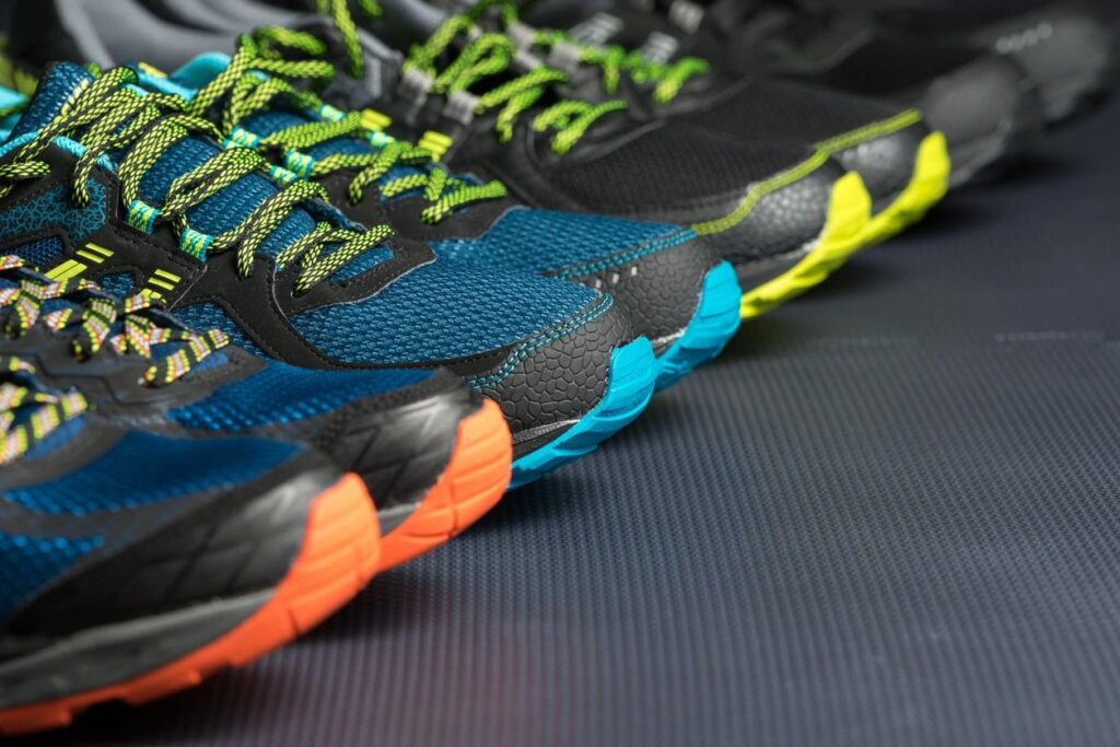 Four pairs of athletic shoes on a gym mat.