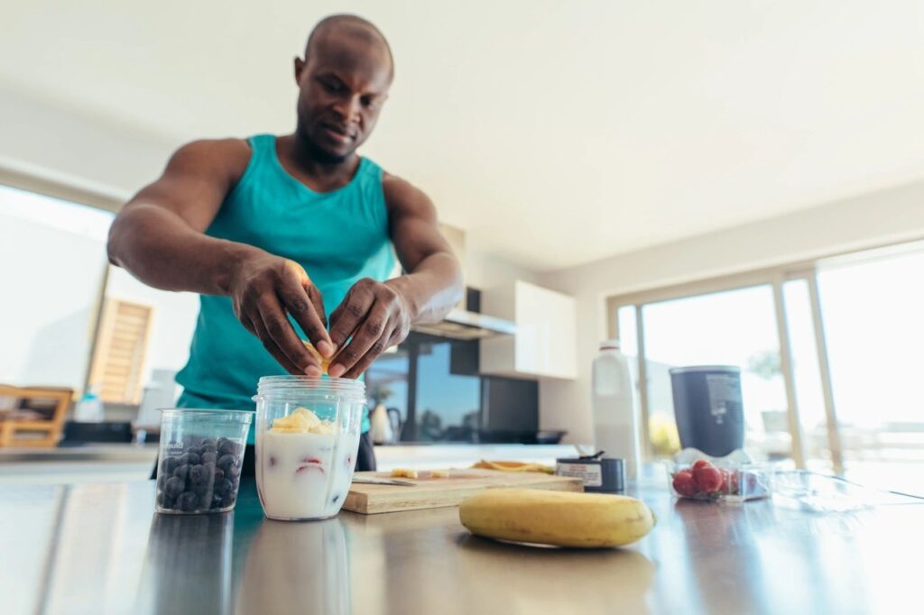 A man making a post-running smoothie with fruits and veggies.